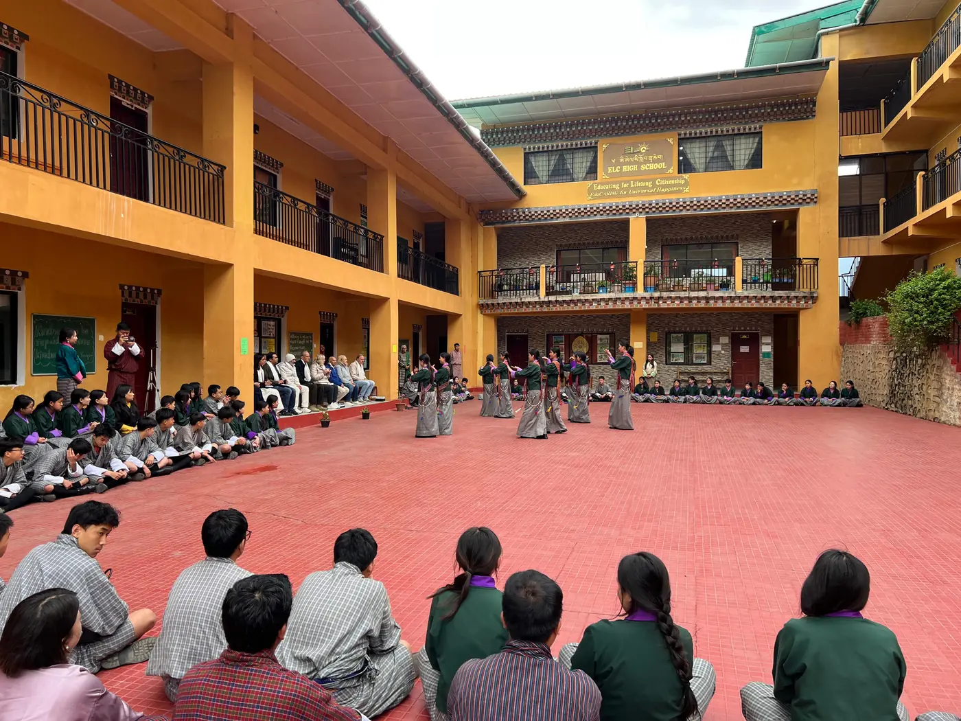 The whole school seated around the edge of the courtyard watching a student performance